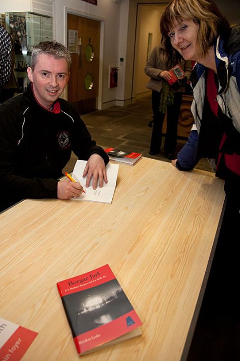 Brydon Leslie signing a copy of his book on Up Helly Aa founder JJ Haldane Burgess for Shetland archaeologist Val Turner.