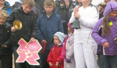 Belle Spence (in white) is joined by 40 others on Unst's Skaw beach and around the country to ring in the 2012 Olympic Games. Pic. Shetland Arts