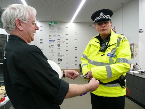 Stuart Hubbard holds out the Mareel opening ribbon for PC Barry Derbyshire to cut at Saturday's all day opening ceremony. Pic. Shetland News