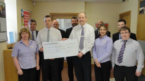 Lerwick Clydesdale Bank manager Rod MacLeod hands the large cheque over to Jim Livitt of the memorial committee. Back (from left): Robbie Leask, Alistair Carnie, Steve Knowles, Andy Forteath, David Coles. Front: Angela Duncan, Jim Livitt, Rod MacLeod, Shannon Moreland and Chris Duncan. Absent from the photo is Craig Spowart.