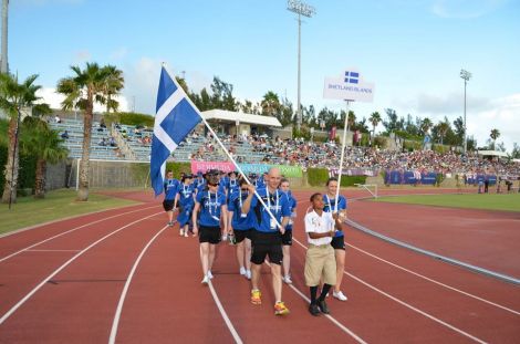 Runner Karl Simpson, swimmer Andrea Strachan and keen cyclist Aaron, aged nine from Bermuda, lead Team Shetland out into the National Stadium for the opening ceremoiny on Saturday evening. Photo Andrew Inkster