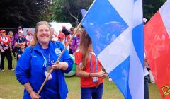 Silver medal winning hammer thrower Elaine Park can't take the grin off her face as she wields the Shetland flag at the closing ceremony in Jersey. Photo: Shetland Island Games Association