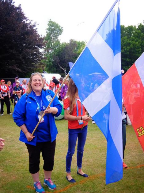 Silver medal winning hammer thrower Elaine Park can't take the grin off her face as she wields the Shetland flag at the closing ceremony in Jersey. Photo: Shetland Island Games Association