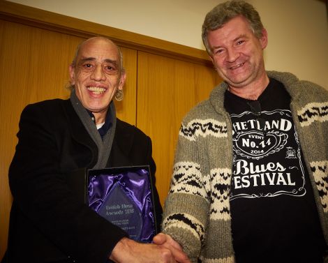 Norman Watt-Roy receives the British blues award for best bass player in 2015 from Shetland Blues Festival organiser Jimmy Carlyle - Photo: Chris Brown