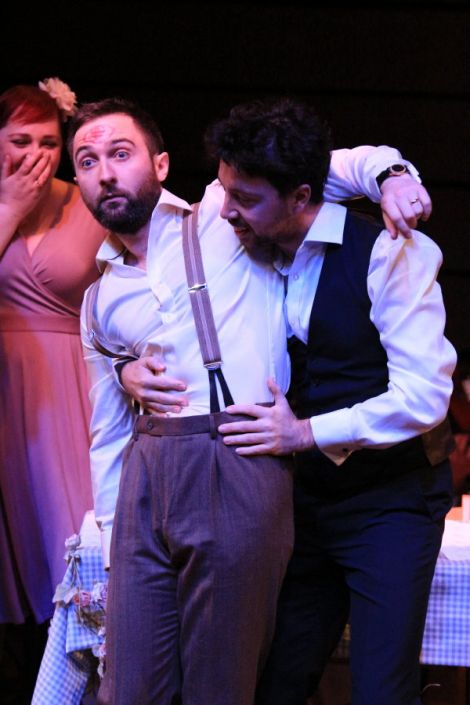 Andrew Dickenson (Iain) is carried by Douglas Nairn (Alasdair) with soprano Shuna Sendall (Elsa) in the background. 