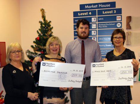 Toby Sandison of Scalloway Boating Club presenting cheques to Mind Your Head and the Shetland branch of Alzheimer Scotland.