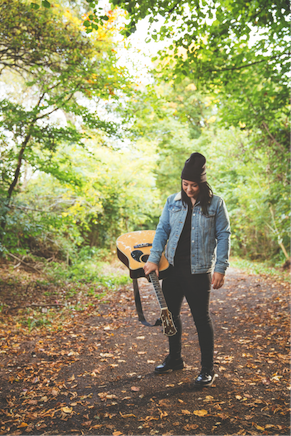 Lucy Spraggan and her guitar in the woods.