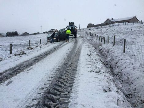 A tractor comes to the aid of a car after it slides off the road in Aith. Photo: Lewis Fraser