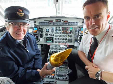 Wing commander Christine Copsey holding the baton in the cockpit of a Loganair Saab 340.