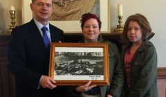 Council convener Malcolm Bell accepts the artwork from Shetland Supports Refugees founder Wendy Sinclair (centre) and her daughter Lainey Sinclair (right).