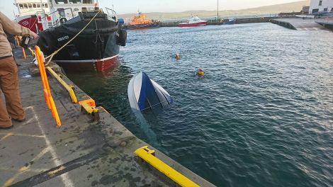 The overturned boat shortly before being lifted from the harbour - Photo: Caroline Watt/Shetland News