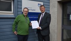 NHS Shetland chief executive Ralph Roberts (right) receiving a paper petition with over 500 signatures from Bob Birchall. Photo: Shetland News