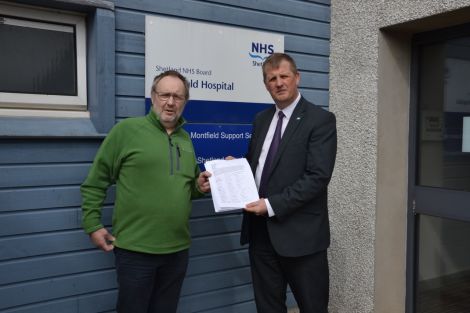 NHS Shetland chief executive Ralph Roberts (right) receiving a paper petition with over 500 signatures from Bob Birchall. Photo: Shetland News