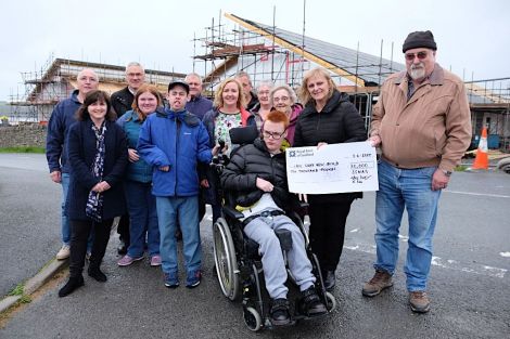 John Hunter, Chair of Shetland Special Needs Action Group (right), presents a cheque for £10,000 to Connie Russell, Team Leader – Eric Gray Resource Centre, towards the Hansel Fund for the new building. Back row (l to r) – Chris Pulley, Neil Risk, Kenny Groat, Davy Napier, Thelma Leslie. Front row: Janne Glesnes Martin (EGRC), Katie Hunter, Paul Ditchburn, May MacDonald, Doreen Williamson, Connie Russell and John Hunter. Centre Front – Dylan McDougal. Photo: SIC