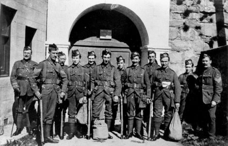 The local unit of army reservists were mobilised for full-time war duty in August 1914.  The next year, as military losses on the western front increased, the Shetland Gordon Highlanders left for mainland army bases, then moved onward to France.  Here, a group are seen at the gate of Fort Charlotte on the day they left on the troopship at Lerwick, and later the whole unit is assembled at a base in mainland Britain. Photo: Courtesy of Shetland Museum.