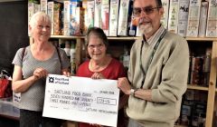 Christine Henderson and Helen Burgess donate a cheque to foodbank manager David Grieve.