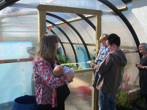 Archer Simmons cuts the ribbon, helped by dad Andrew and watched by Dr Susan Bowie, holding Maisie Simmons, and (on the right) Pam Muir.