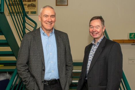 Two men in business suits standing next to stairs.