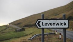 A black and white sign on the side of a road.