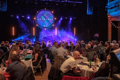 A crowd of people sitting at tables in an auditorium.