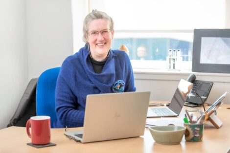 A woman sitting at a desk with a laptop in front of her.