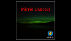 A dark night sky with green auroras and text "Mirrie Dancers" in red. The bottom right corner has an illustrated yellow circular logo with a blue background and the text "I Hear Dee.