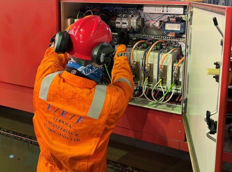 A technician in protective gear works on an open electrical control panel labeled "L.E.F. Lenrick Engineering & Fabrication Ltd.