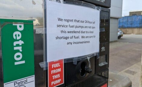 A sign on a fuel pump reads, "We regret that our 24 hour self service fuel pumps are not open this weekend due to a local shortage of fuel. We are sorry for any inconvenience.