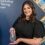 A person in a black dress holding an award stands in front of a backdrop that reads "Royal College of Nursing Scotland.