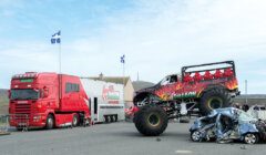 A red monster truck on top of a car.