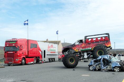 A red monster truck on top of a car.