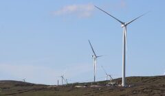 Wind turbines placed on a hilly landscape under a clear sky.