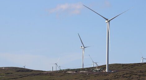 Wind turbines placed on a hilly landscape under a clear sky.