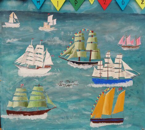 Colorful illustration of multiple sailing ships on the ocean, with bunting flags spelling "SHIP2021" across the top. The water and sky are painted in various shades of blue.