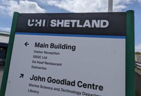 A sign for UHI Shetland directing to the Main Building and John Goodlad Centre with various facilities listed underneath each heading.