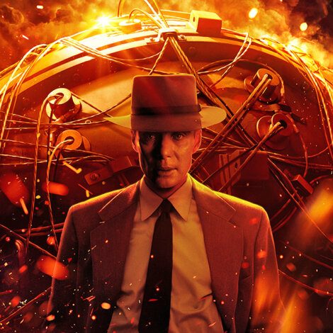 A man in a suit and hat stands in front of a large mechanical device, illuminated by fiery, orange light with wires and components visible.