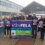 A group of people stand outside a building holding banners and signs advocating for fair pay and job protection, representing the Educational Institute of Scotland, Shetland, and UHI.