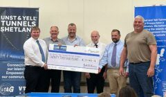 Group of men presenting a large ceremonial check for twenty thousand pounds to a representative of the shetland tunnels project.