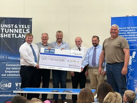 Group of men presenting a large ceremonial check for twenty thousand pounds to a representative of the shetland tunnels project.