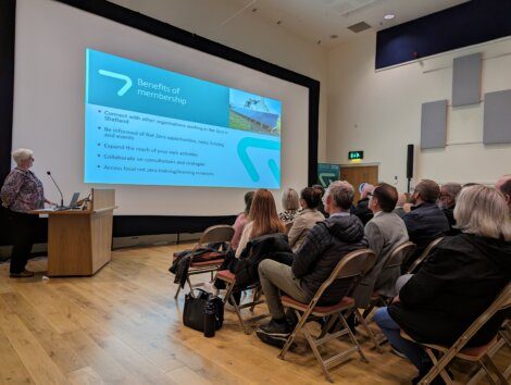 Audience attending a presentation on the benefits of membership in a conference room.