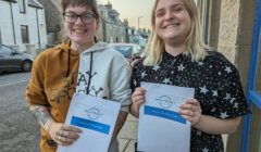 Two smiling individuals holding papers with the text "open project" on the sidewalk.