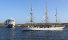 A tall ship sailing close to a modern cruise liner at sea.