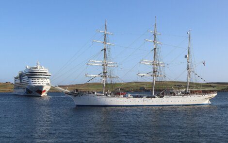 A tall ship sailing close to a modern cruise liner at sea.