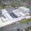 Aerial view of a large school complex with multiple buildings, outdoor playgrounds, and parking areas, surrounded by residential homes and roads.