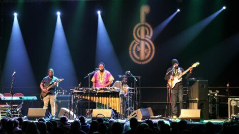 A band performing on stage with a prominent marimba in the spotlight.