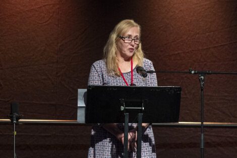 A woman speaking at a podium with a microphone.