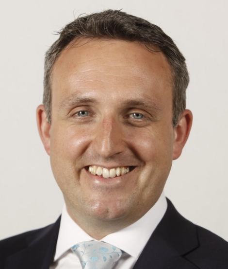 A headshot of a smiling man wearing a suit and tie.