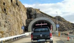 Vehicles waiting at the entrance of a single-lane tunnel with height restriction sign.