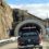 Vehicles waiting at the entrance of a single-lane tunnel with height restriction sign.