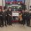 Firefighters posing with community members during a check presentation ceremony at the fire station.